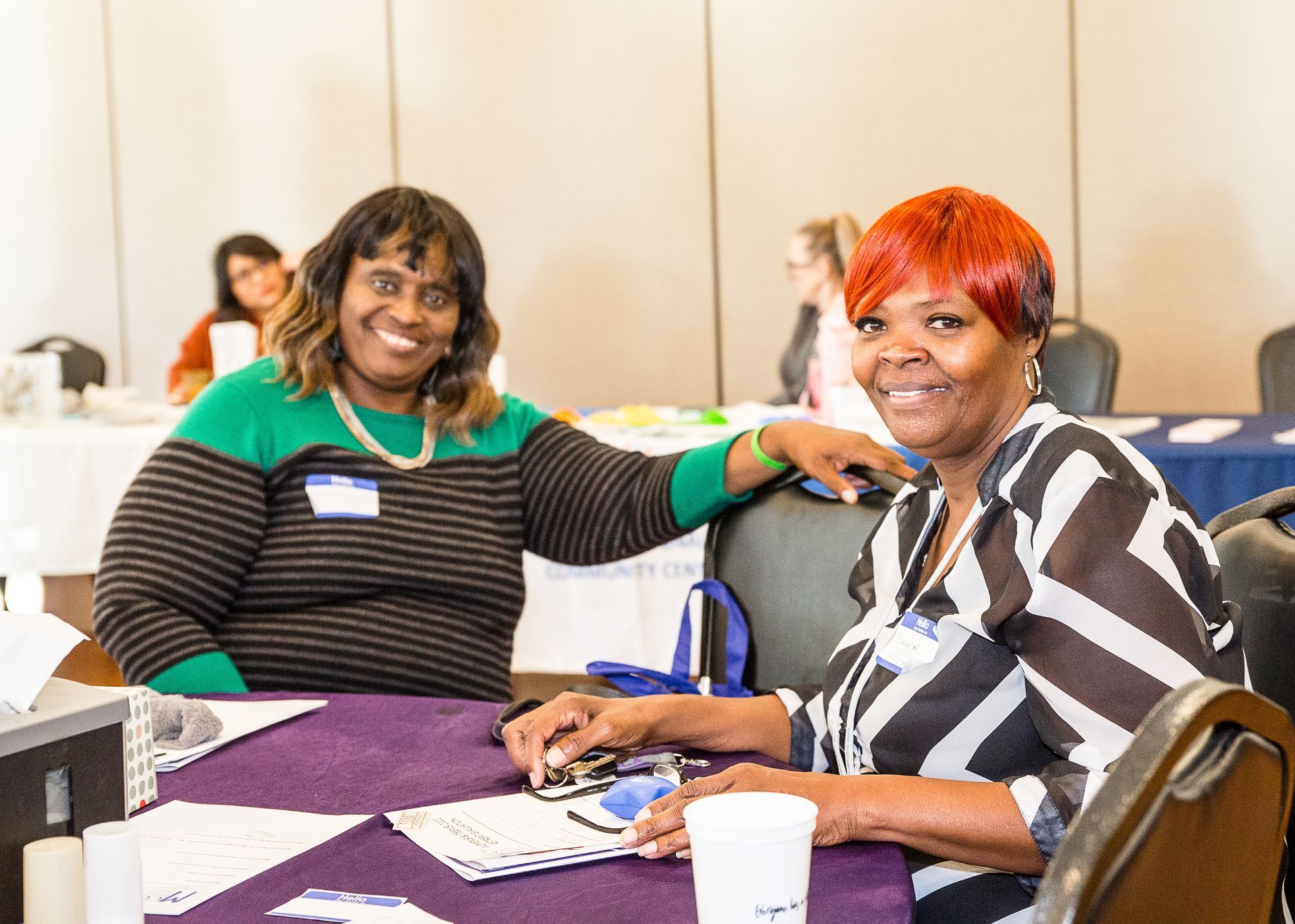 Two women are sitting at a table and smiling for the camera.