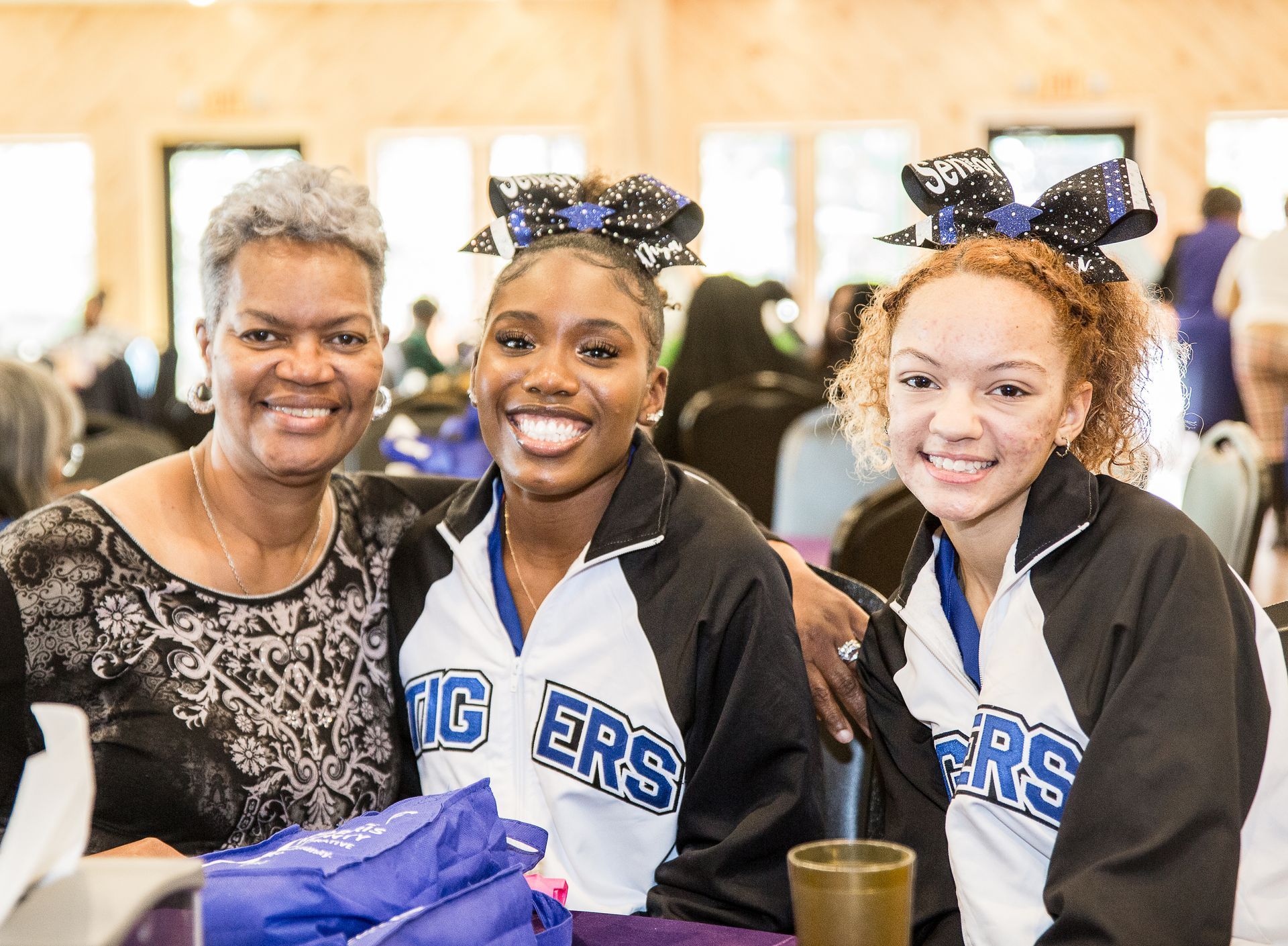 A group of cheerleaders are posing for a picture with a woman.