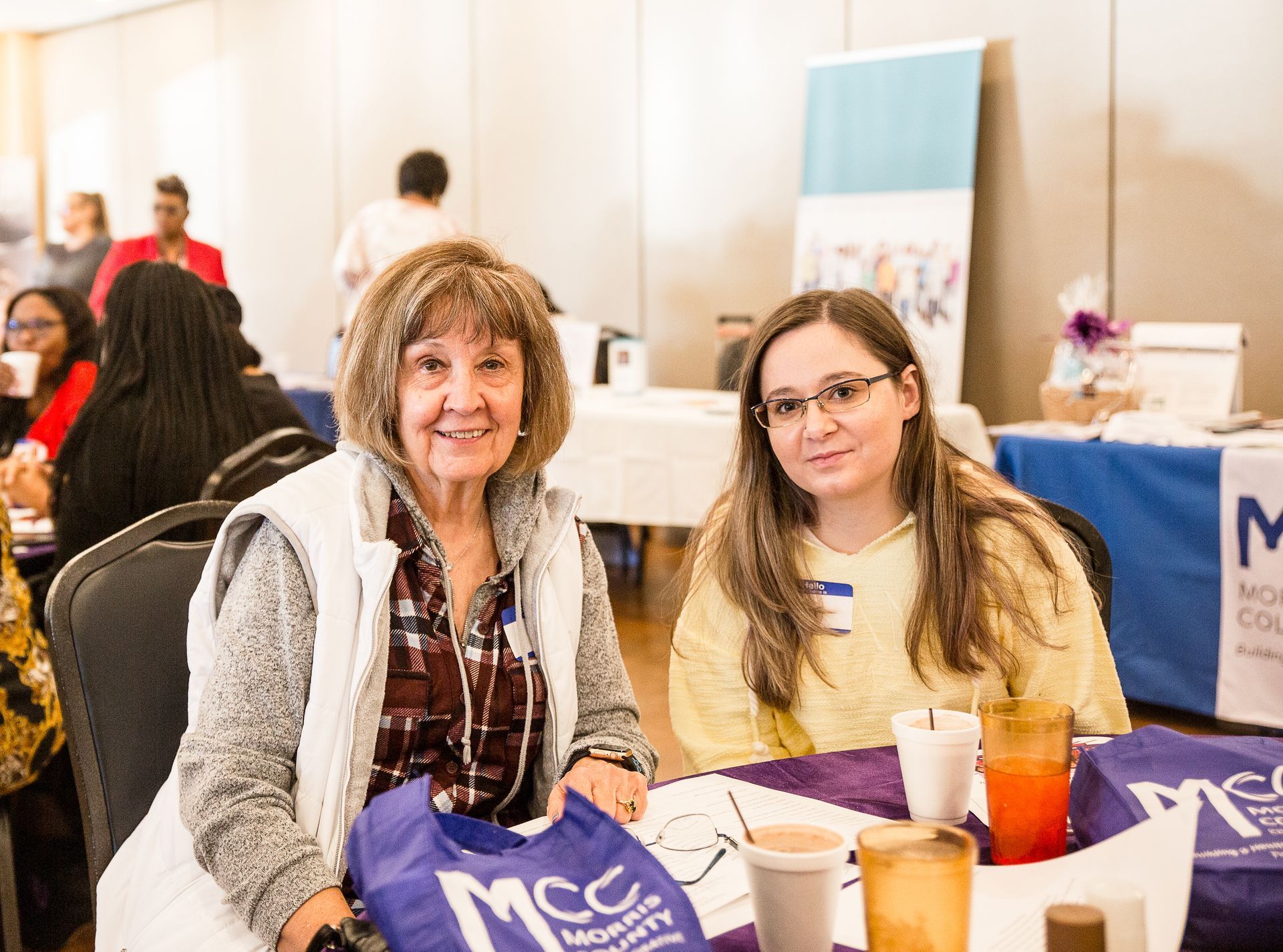 Two women are sitting at a table at a conference.