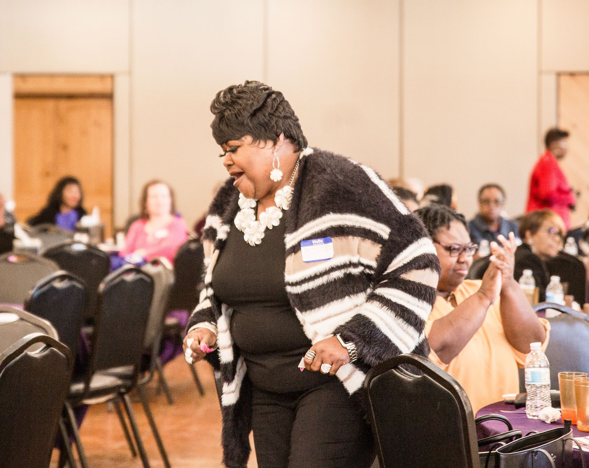 A woman is standing in front of a group of people in a room.