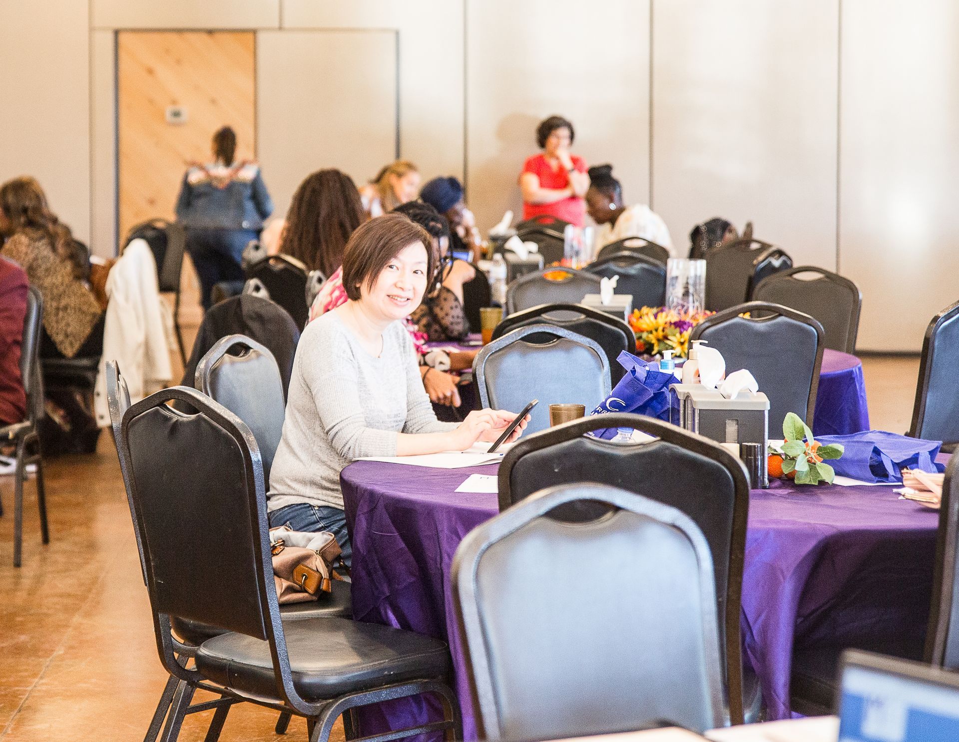 A woman is sitting at a table with a purple table cloth.