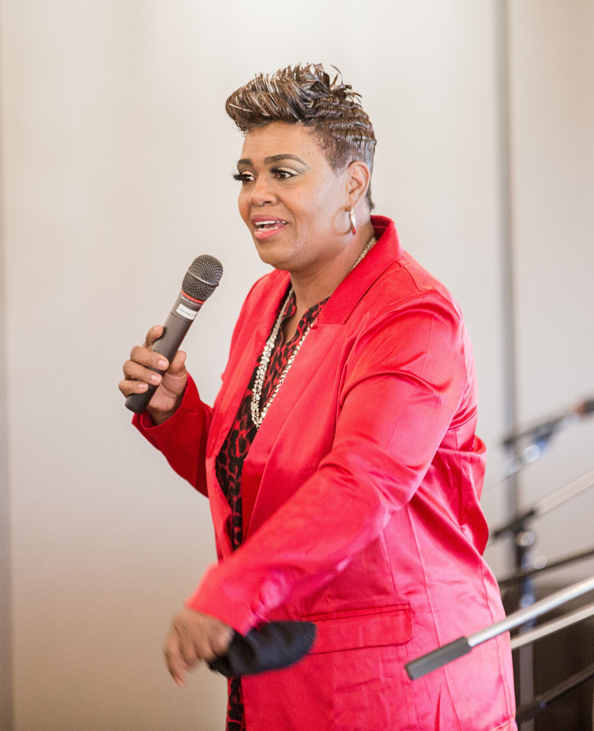 A woman in a red jacket is holding a microphone.