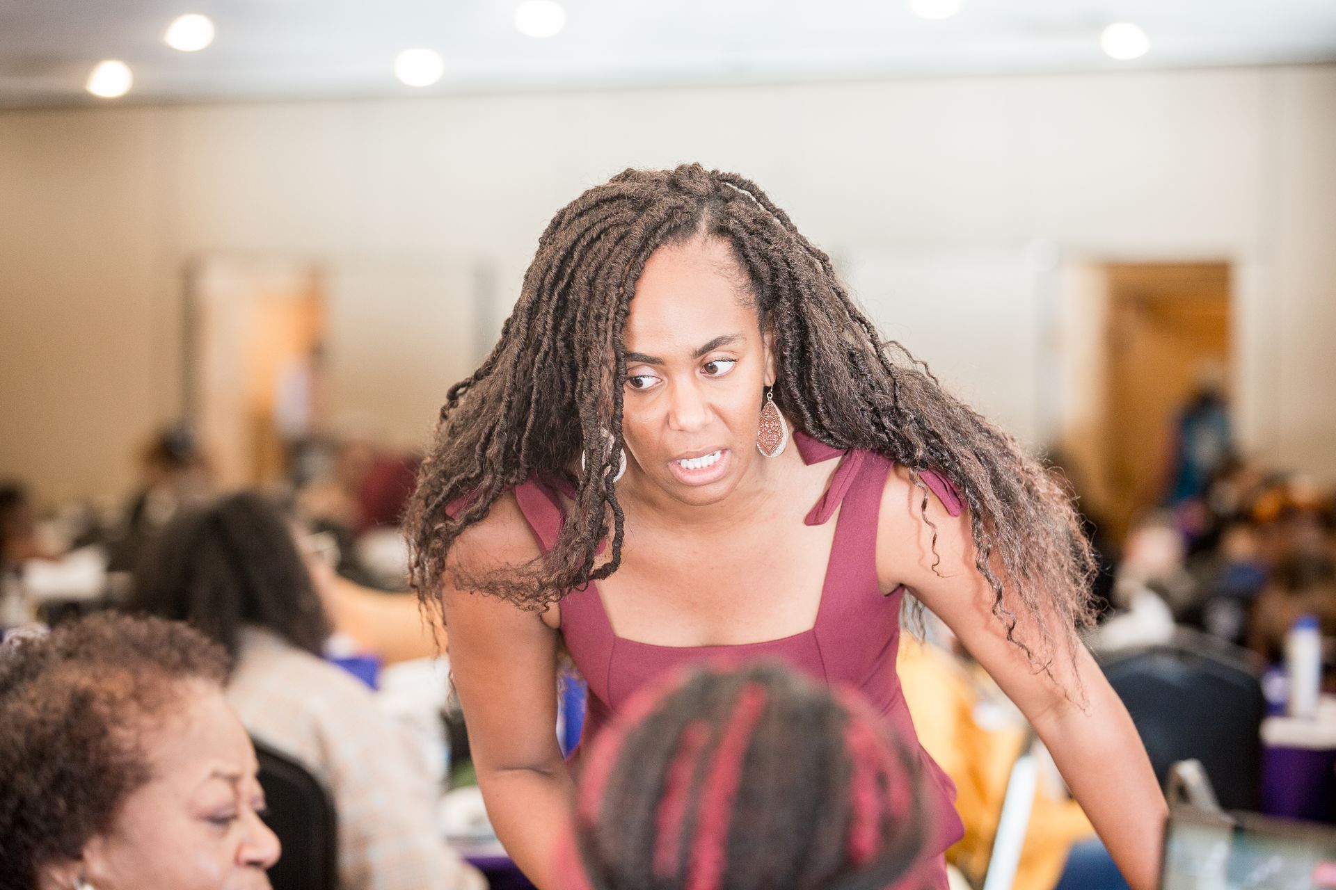 A woman with dreadlocks is talking to another woman in a room.