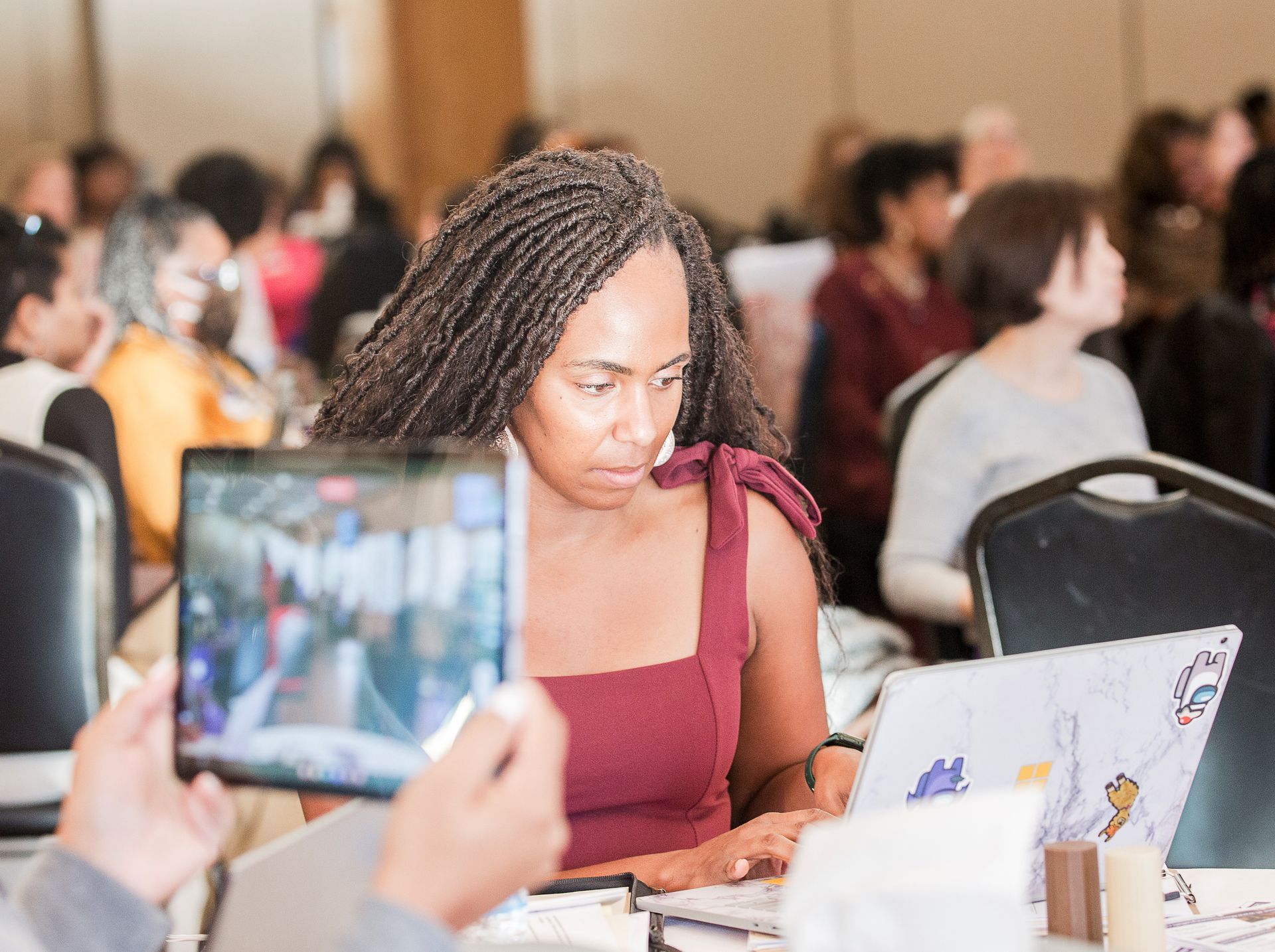 A woman is sitting at a table with a laptop and a tablet.