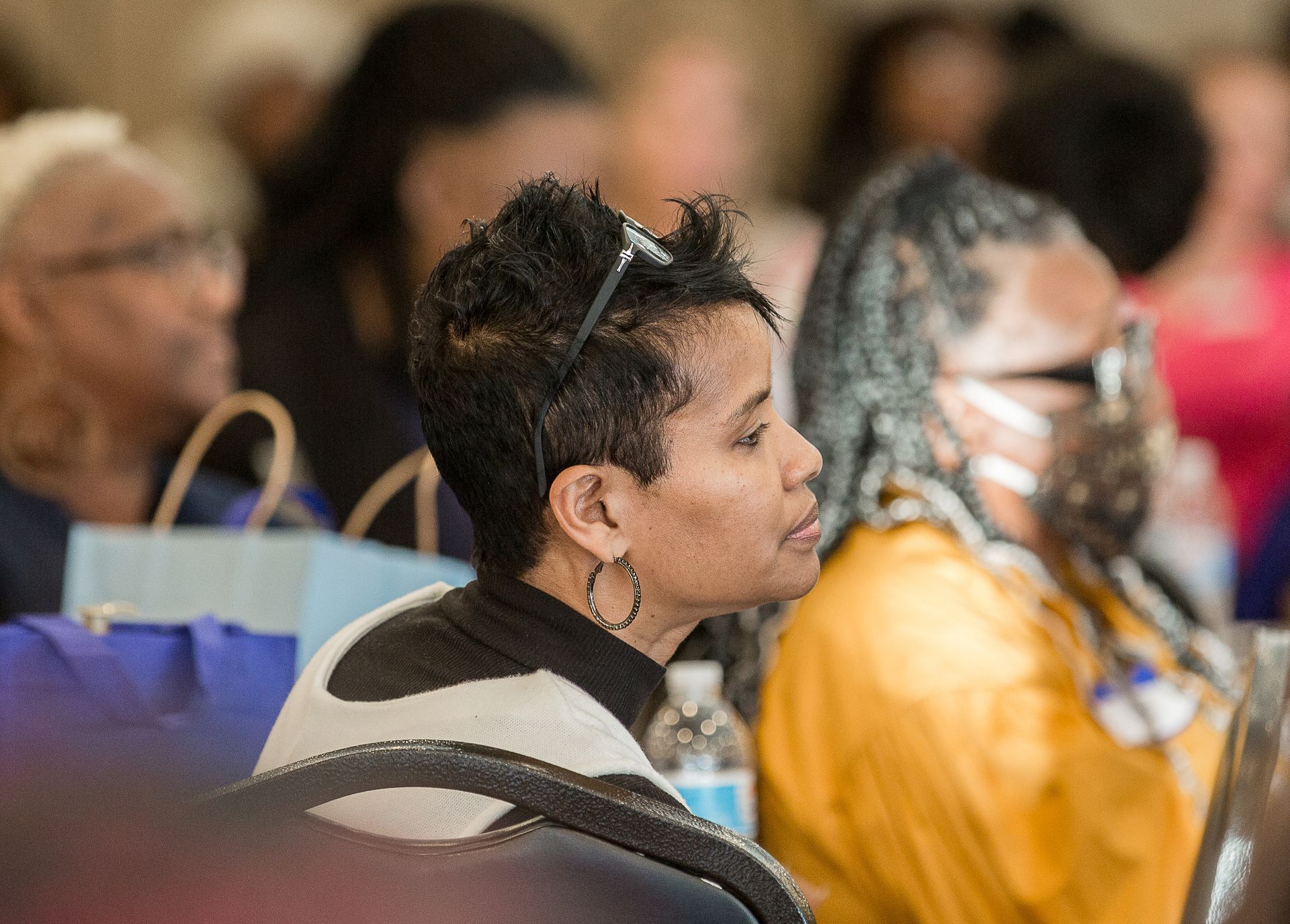 A woman is sitting in a chair in a crowd of people.