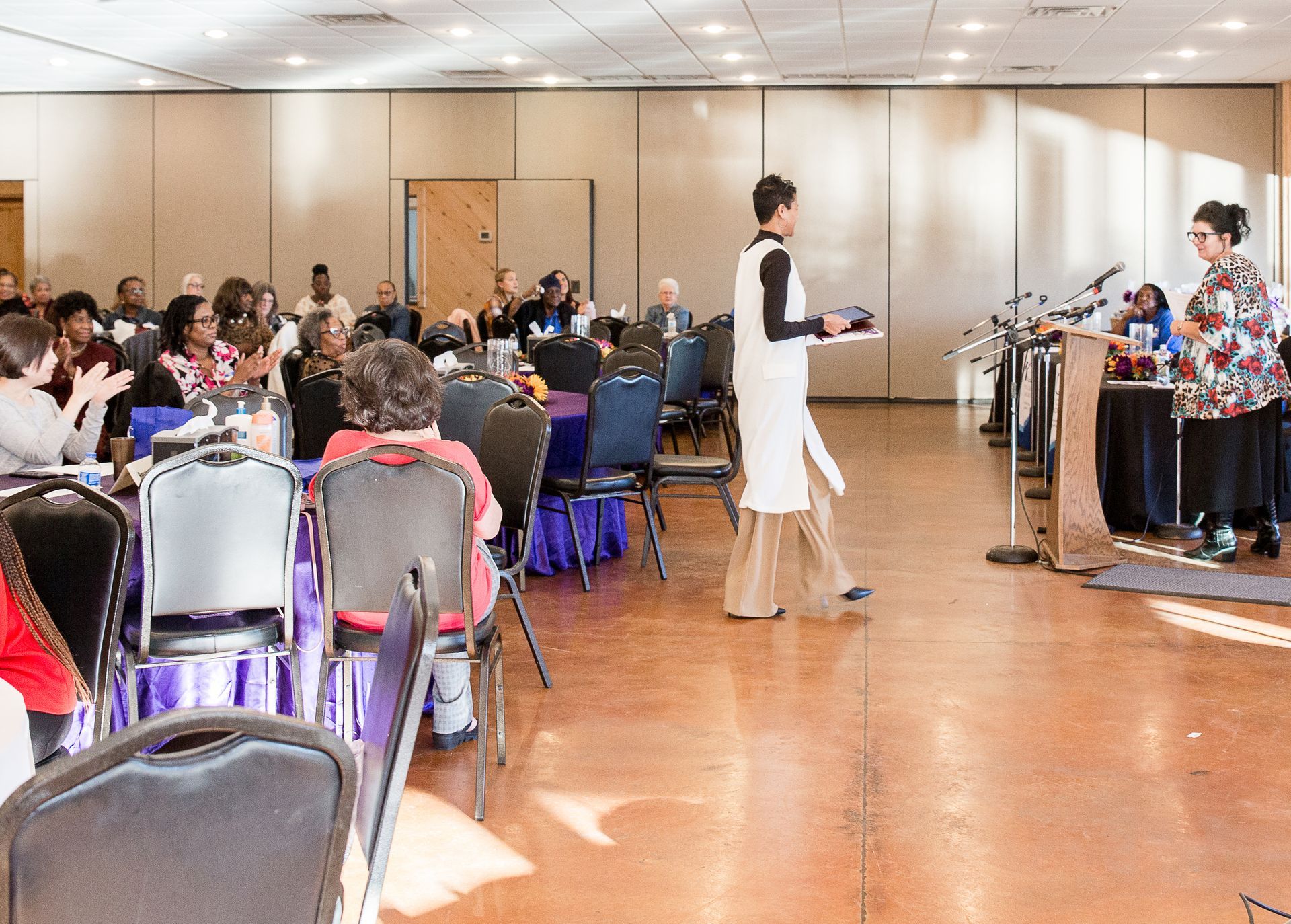 A group of people are sitting at tables in a large room.