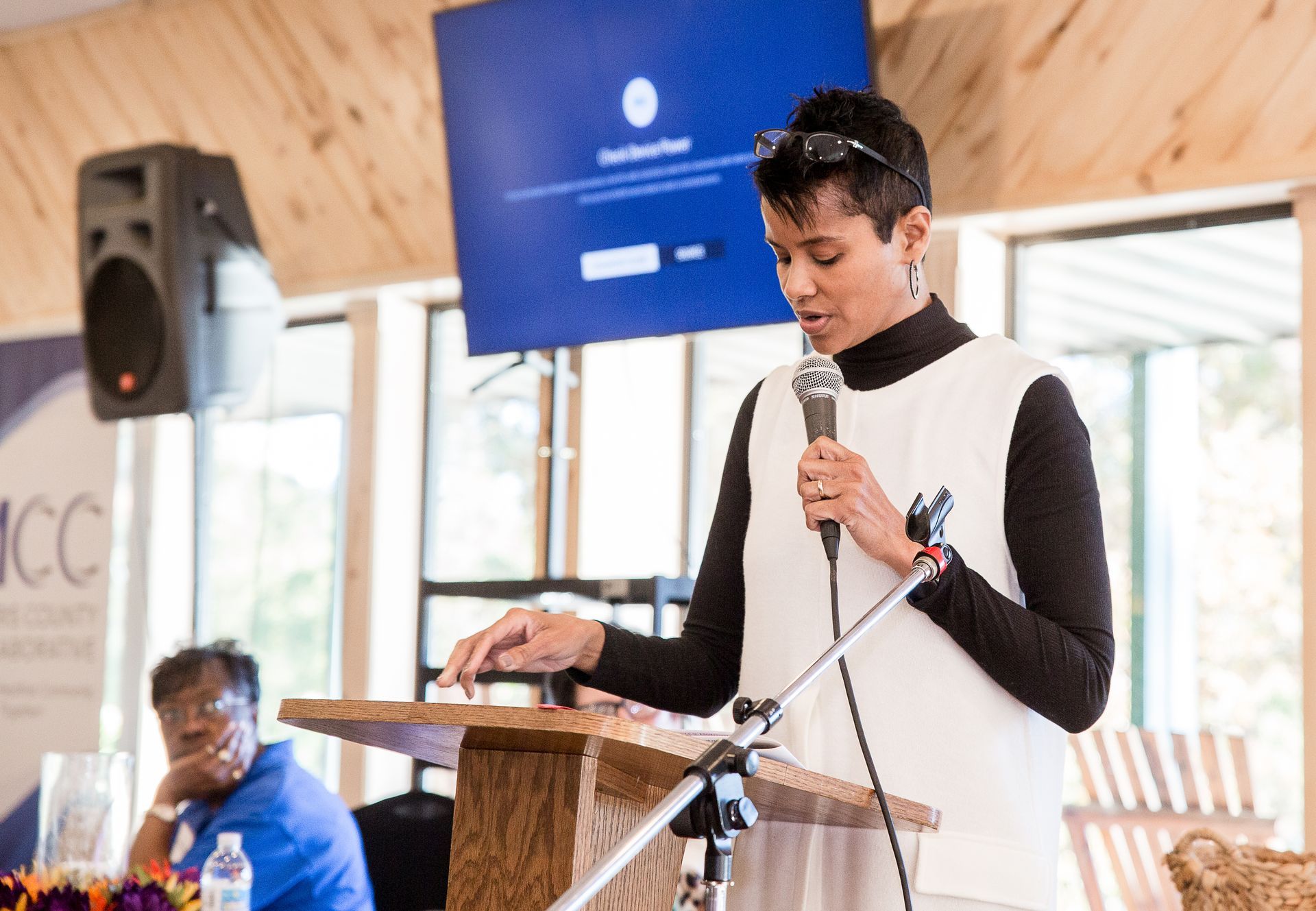 A woman is standing at a podium speaking into a microphone.