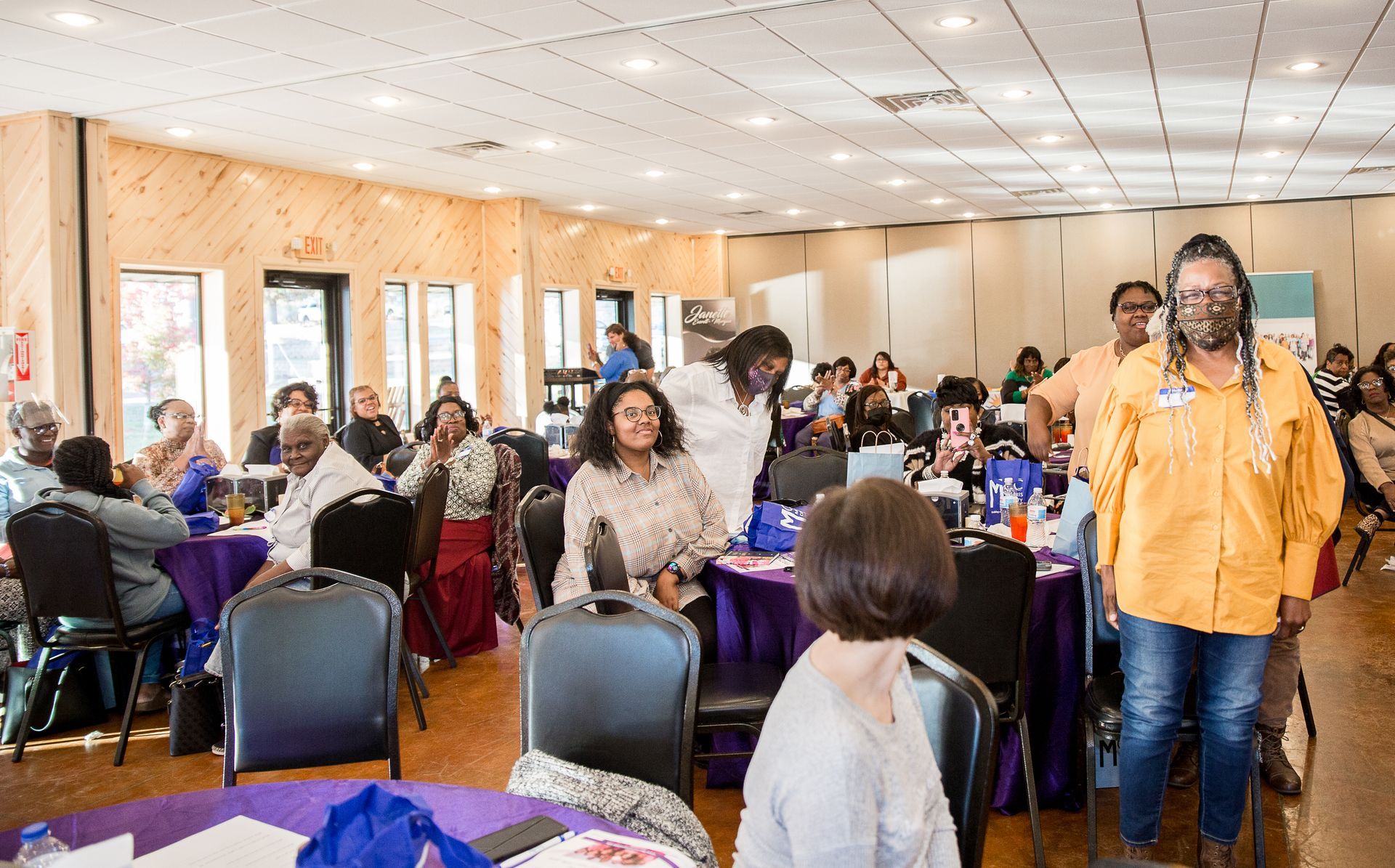A group of people are sitting at tables in a large room.