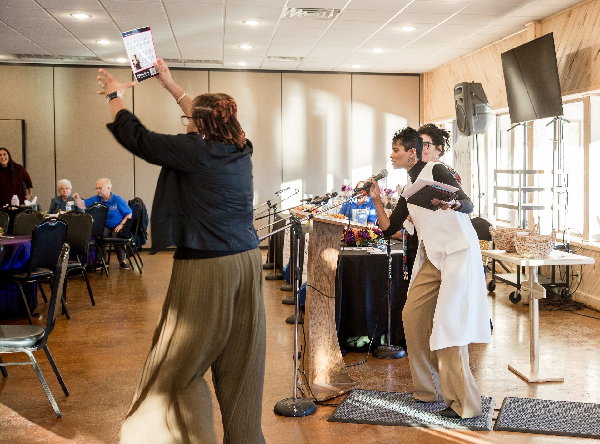 Two women are dancing in a room with microphones.