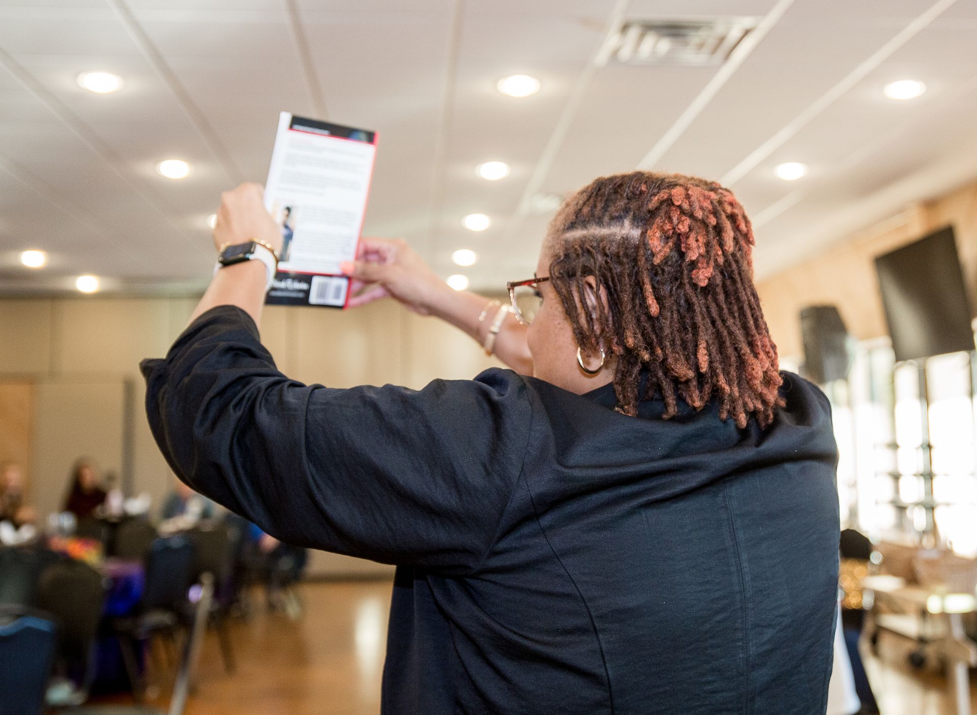 A woman with dreadlocks is taking a picture of herself in a room.