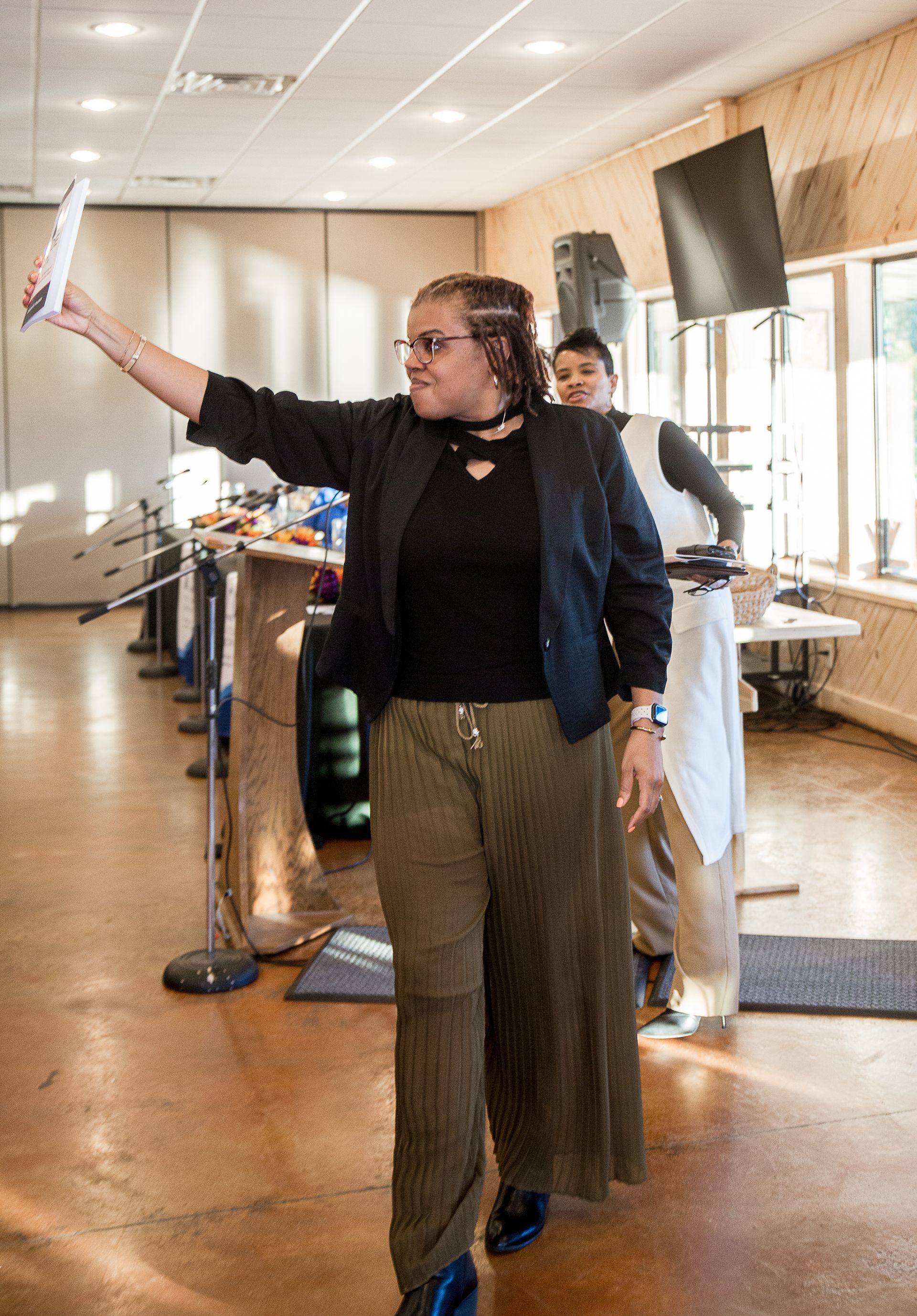 A woman is standing in a room holding a piece of paper in her hand.