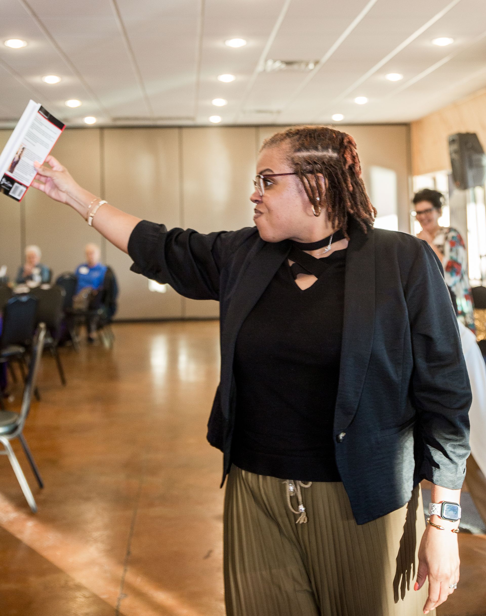 A woman in a black jacket is holding up a piece of paper