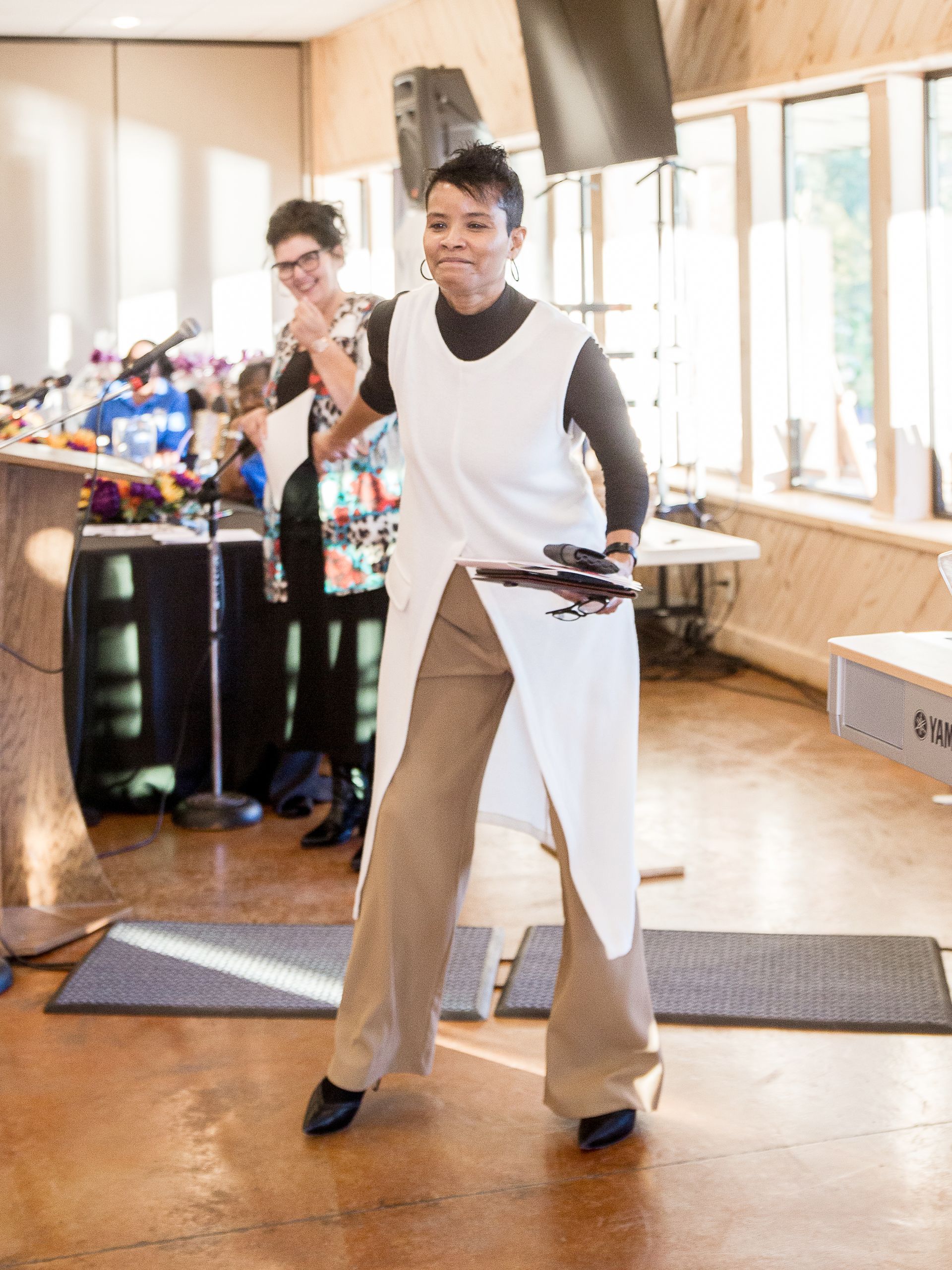 A woman in a white vest is dancing in a room