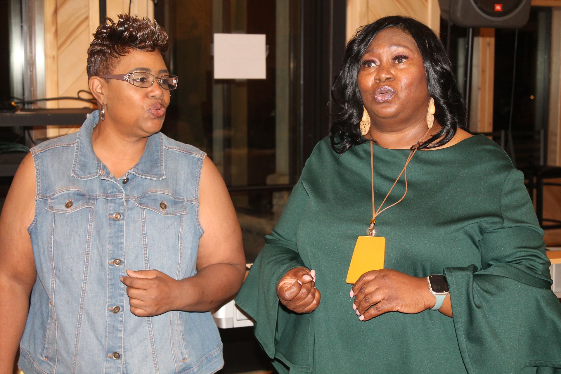 Two women are standing next to each other and talking to each other.