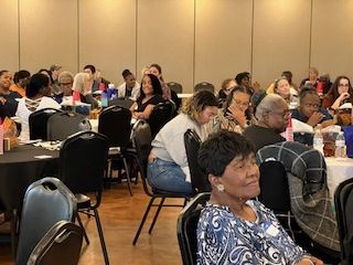 A large group of people are sitting at tables in a room.