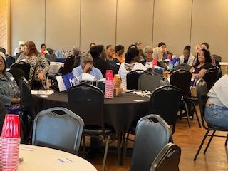 A large group of people are sitting at tables in a room.