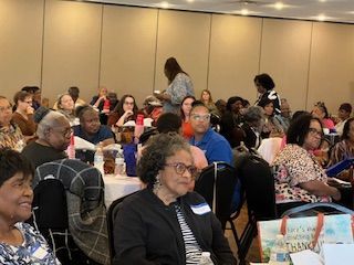 A large group of people are sitting at tables in a room.
