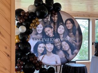 A group of women are standing next to each other in front of a sign that says `` i 'm every woman ''.