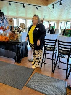 A woman is standing in a room with chairs and tables.