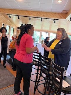 A group of women are standing in a room talking to each other.