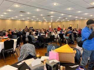 A large room filled with people sitting at tables and chairs.