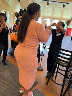 A woman in a pink dress is standing in a room with other women.