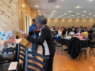 A woman is standing in a large room holding a piece of paper.