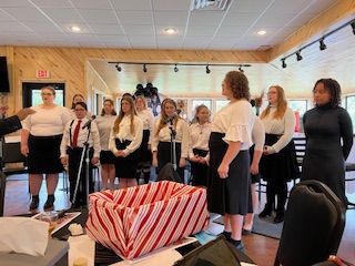 A group of women are singing in front of microphones in a room.