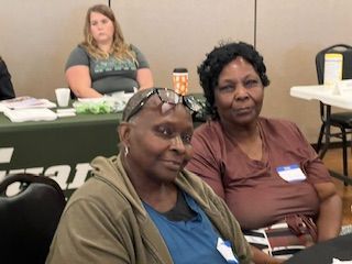 Two women are sitting at a table and smiling at the camera.