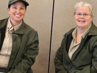 Two women in military uniforms are sitting next to each other and smiling.