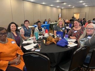 A group of women are sitting at tables in a room.
