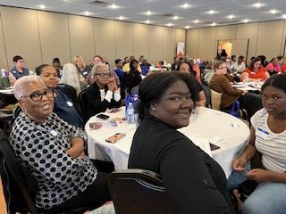 A group of people are sitting at tables in a large room.