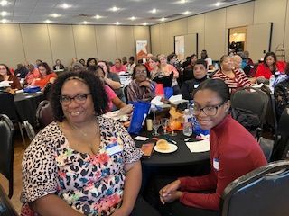 A group of people are sitting at tables in a large room.