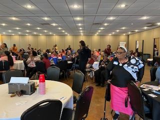 A woman is standing in a large room with tables and chairs.