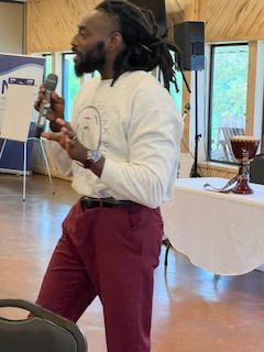 A man with dreadlocks is holding a microphone in a room.