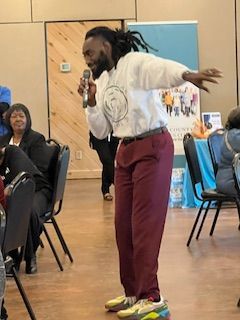 A man is standing in a room holding a microphone.