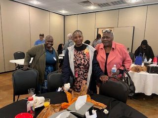 A group of women are standing around a table in a room.
