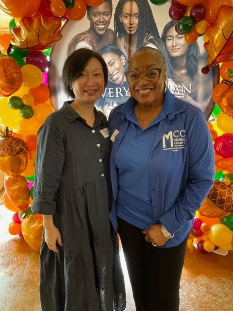 Two women are posing for a picture with balloons in the background