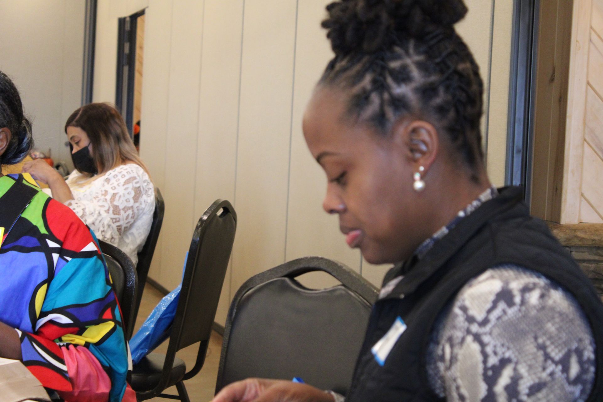A woman is sitting at a table wearing a mask.
