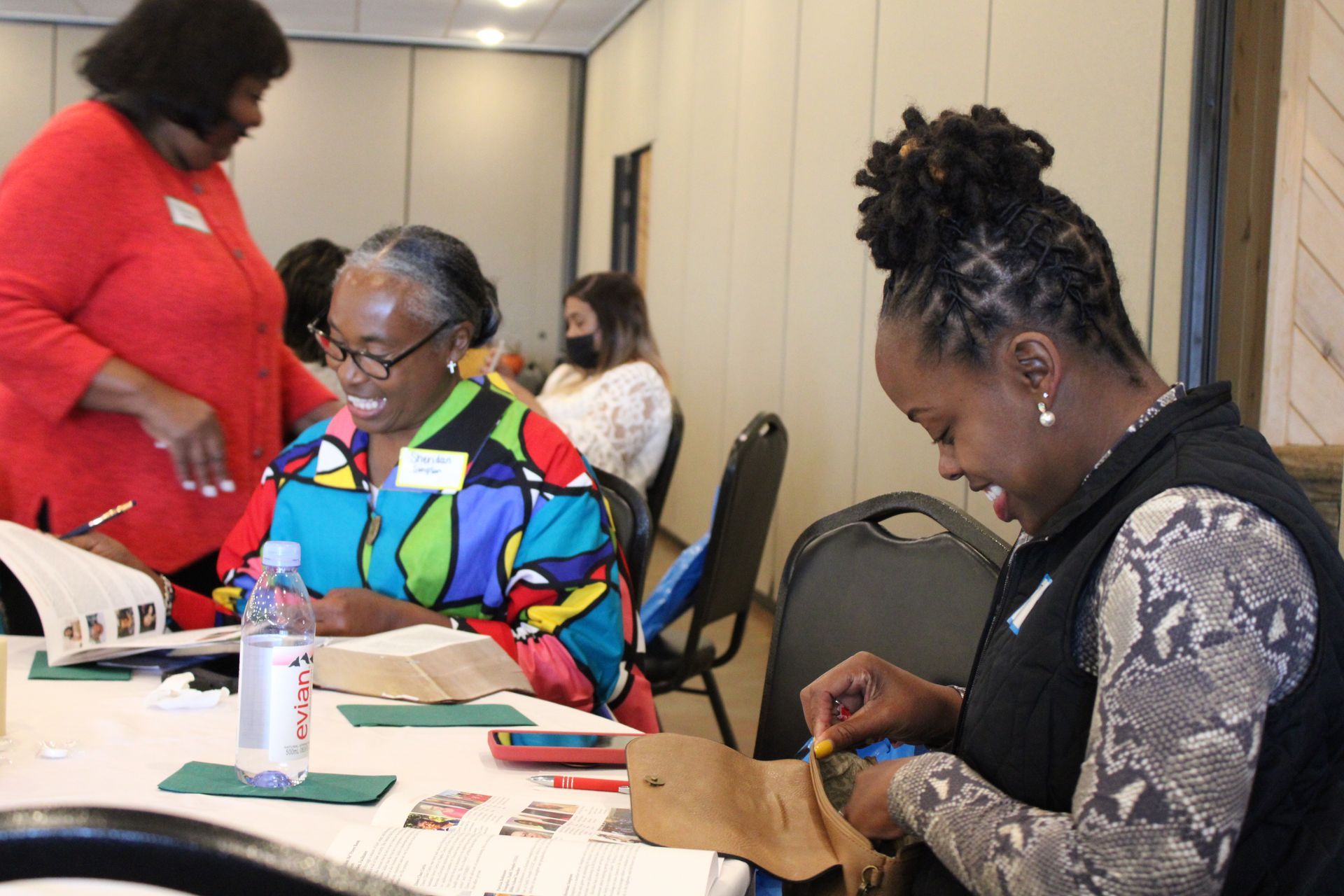 Two women are sitting at a table with a bottle of water.