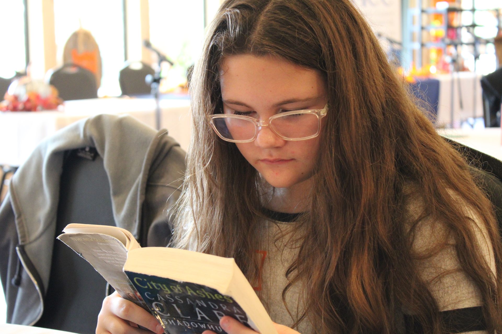 A young woman wearing glasses is reading a book