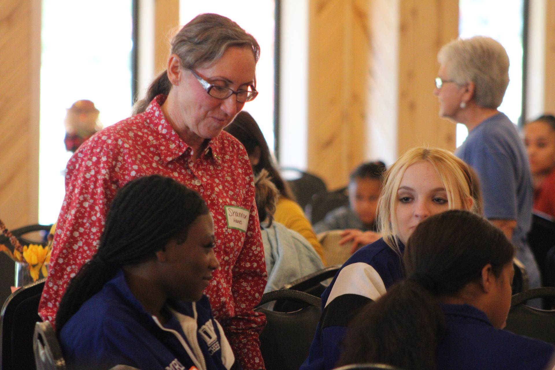 A woman in a red shirt is talking to a group of people