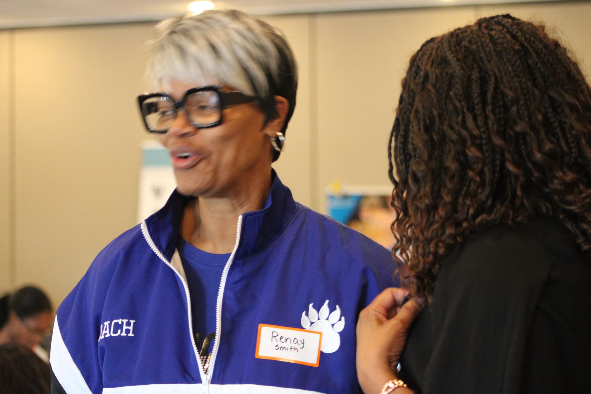 A woman wearing a blue jacket with the name age on it