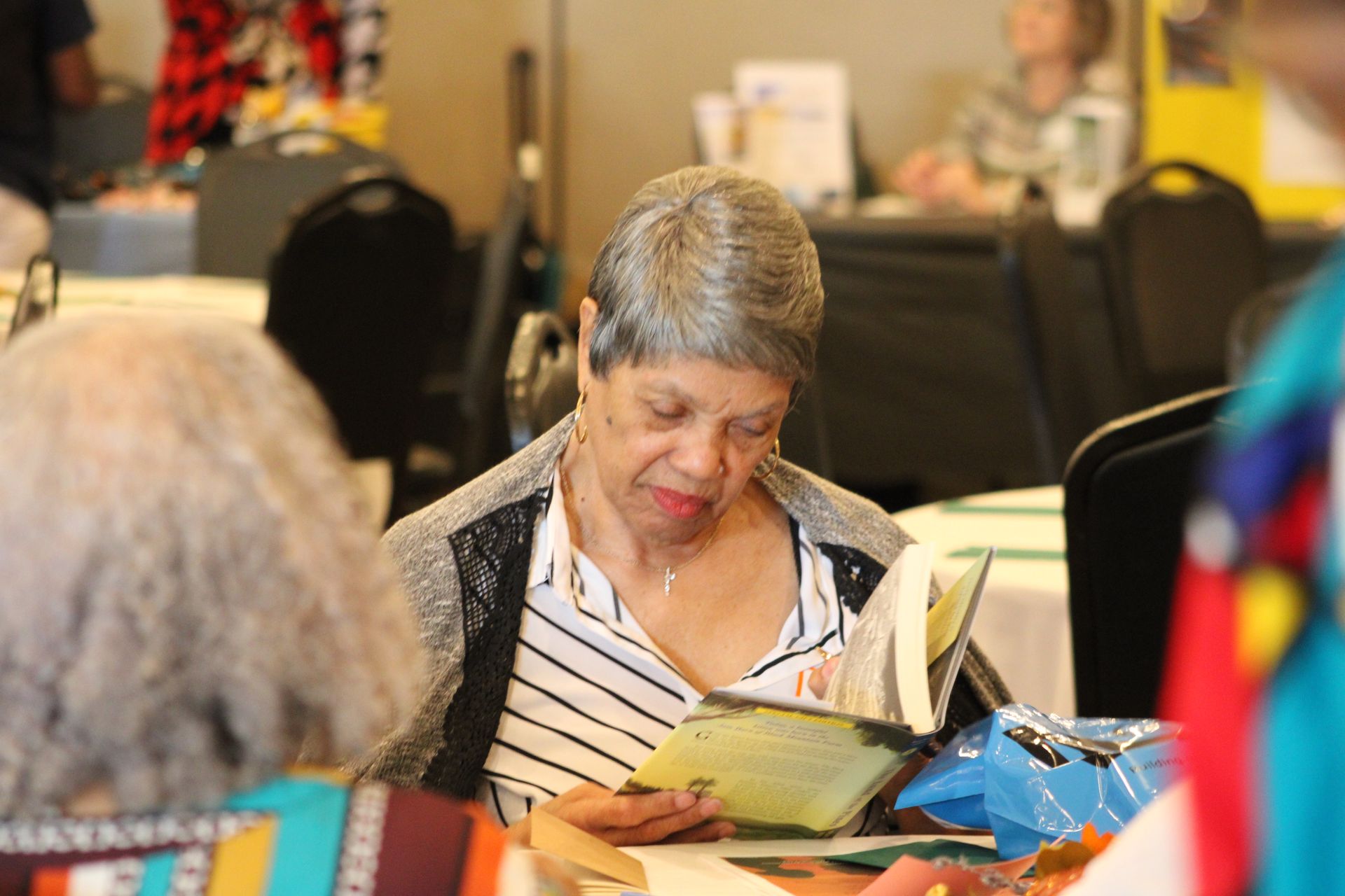 A woman is sitting at a table reading a book.
