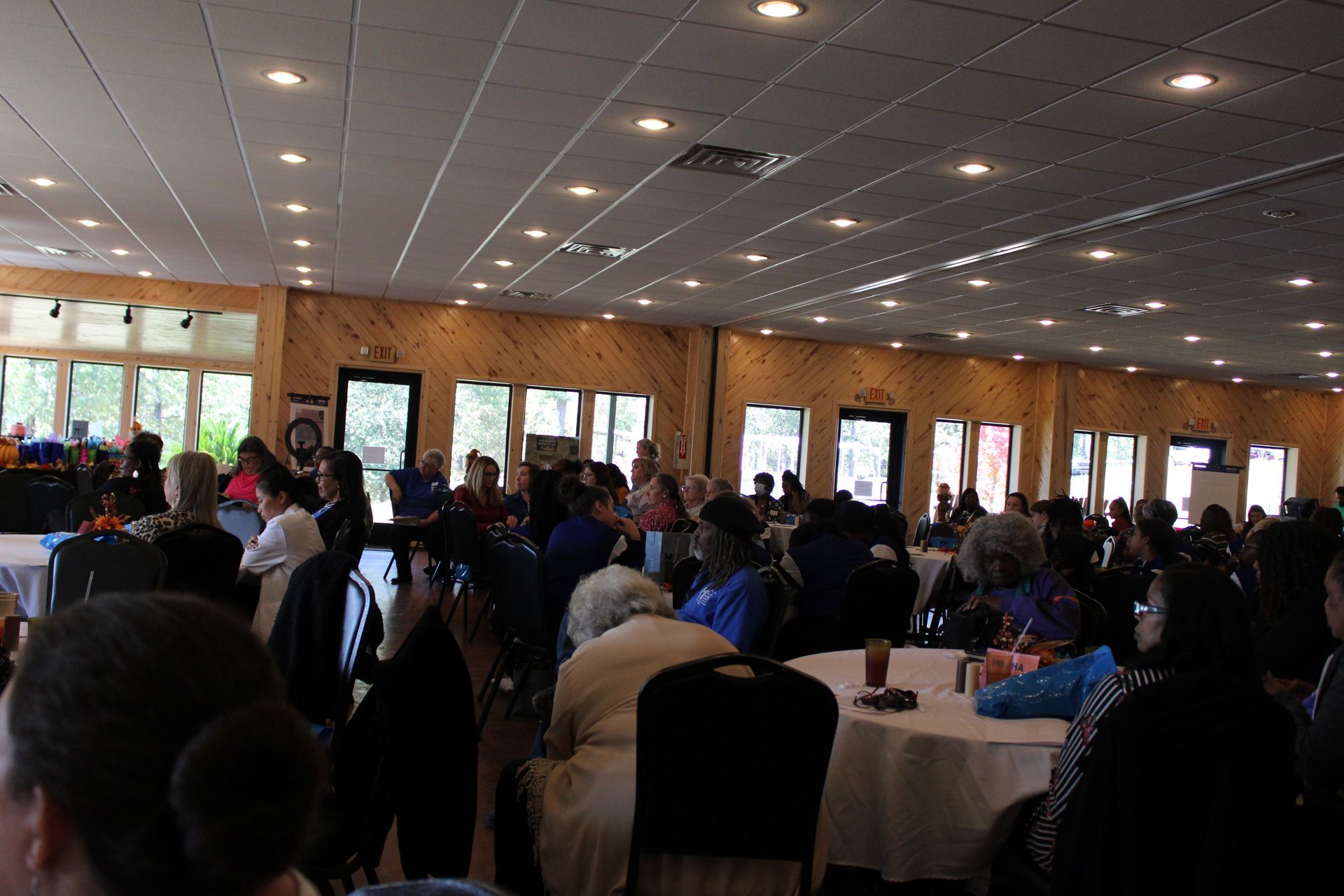 A large group of people are sitting at tables in a large room.