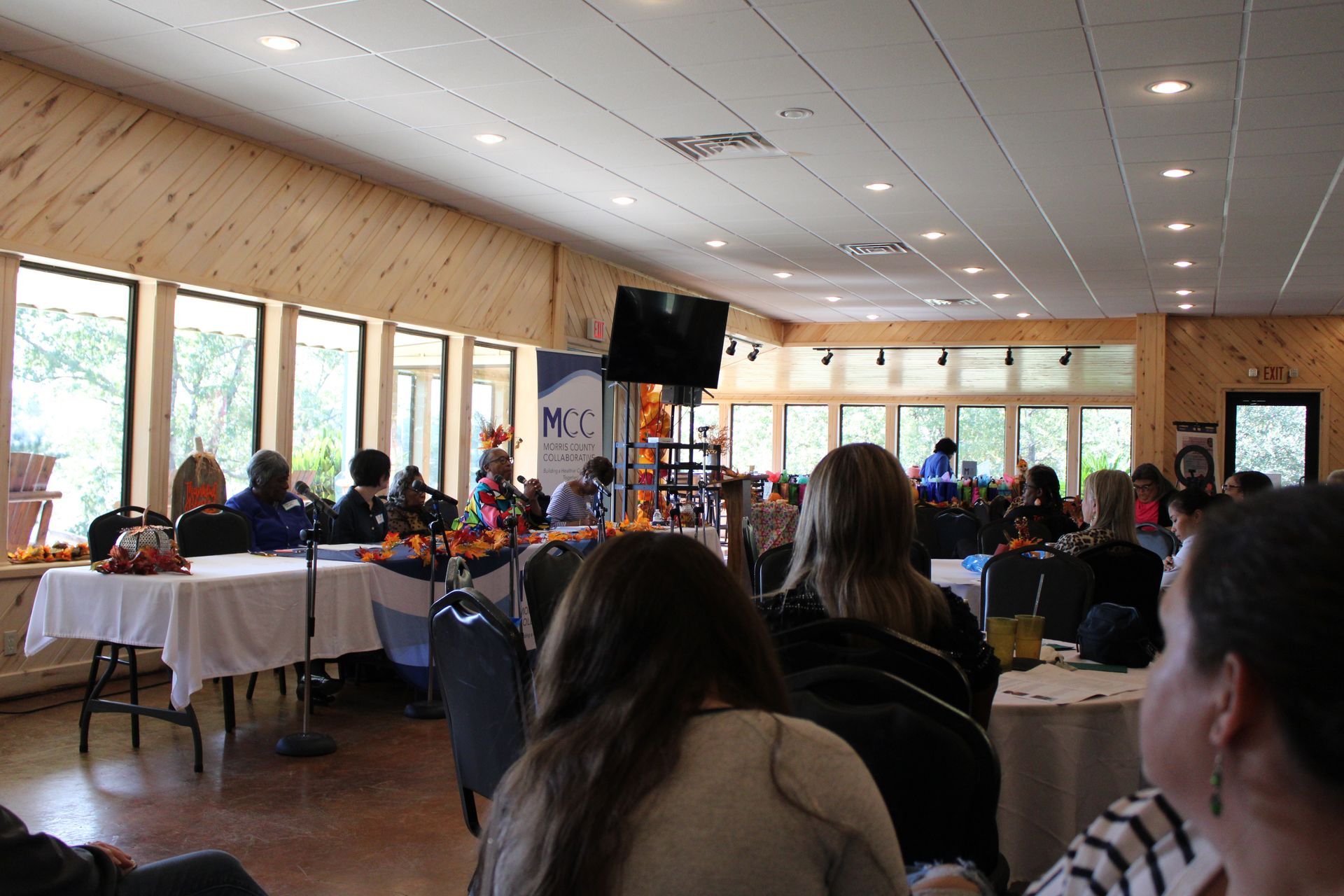 A group of people are sitting at tables in a large room.