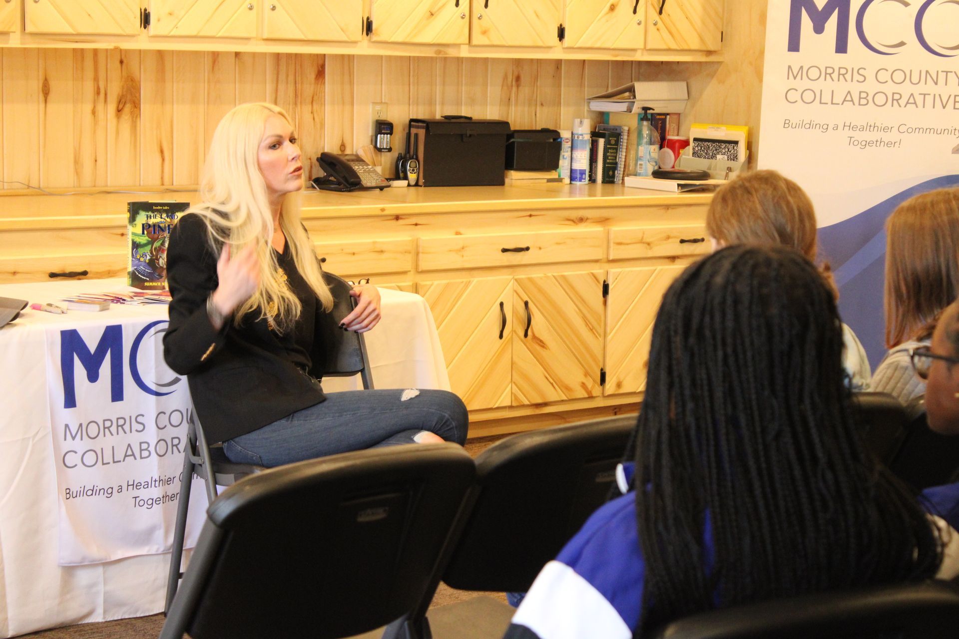 A woman is sitting in a chair talking to a group of people.
