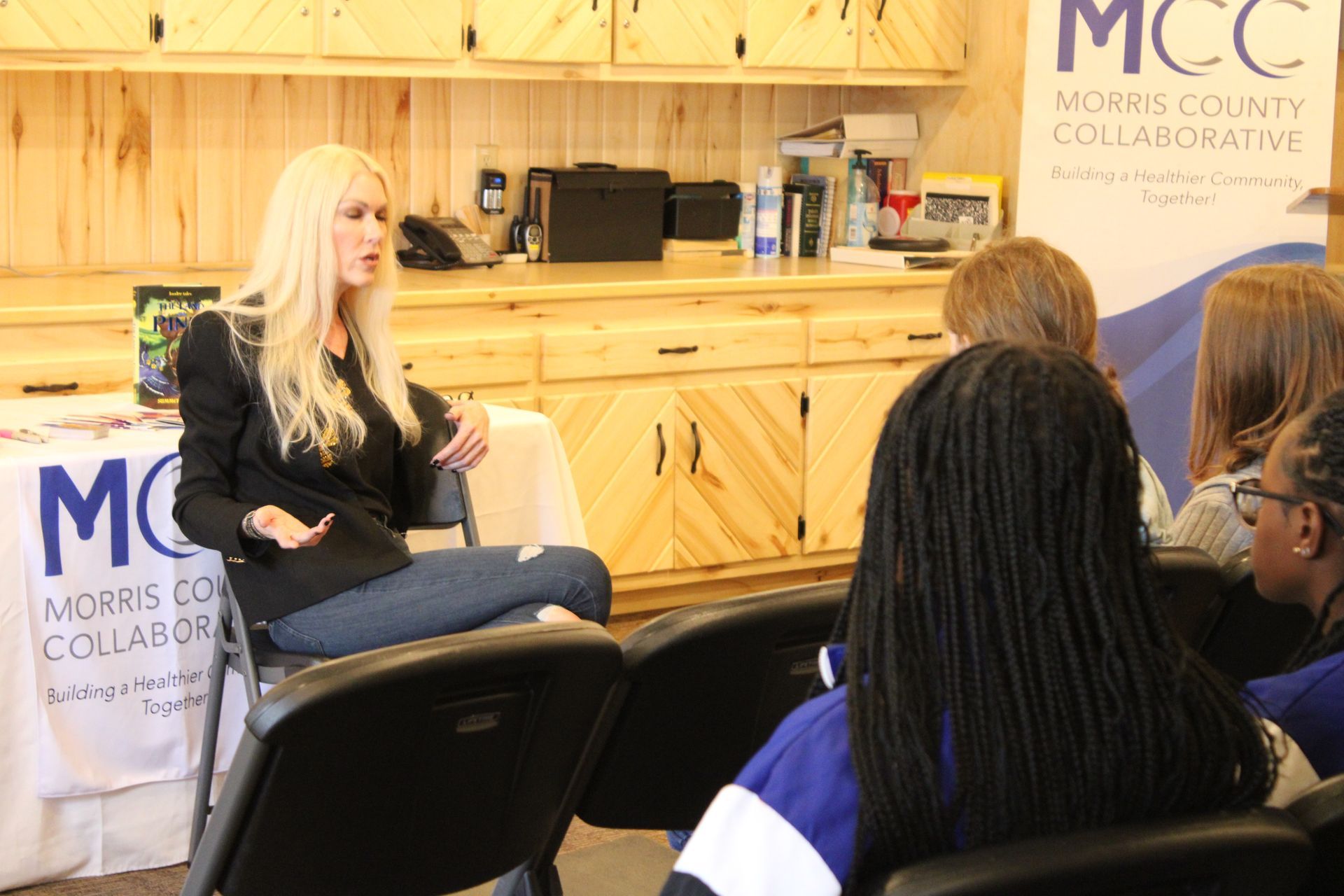 A woman is sitting at a table talking to a group of people.