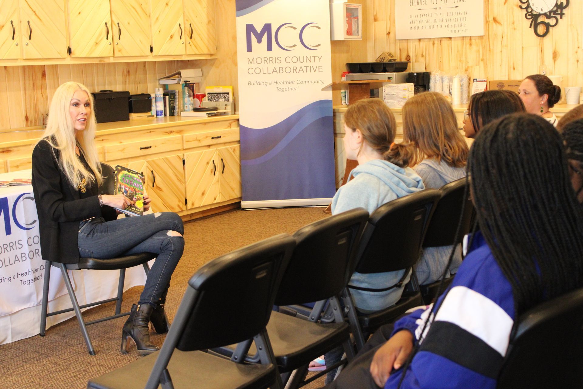 A woman is sitting in a chair talking to a group of people.