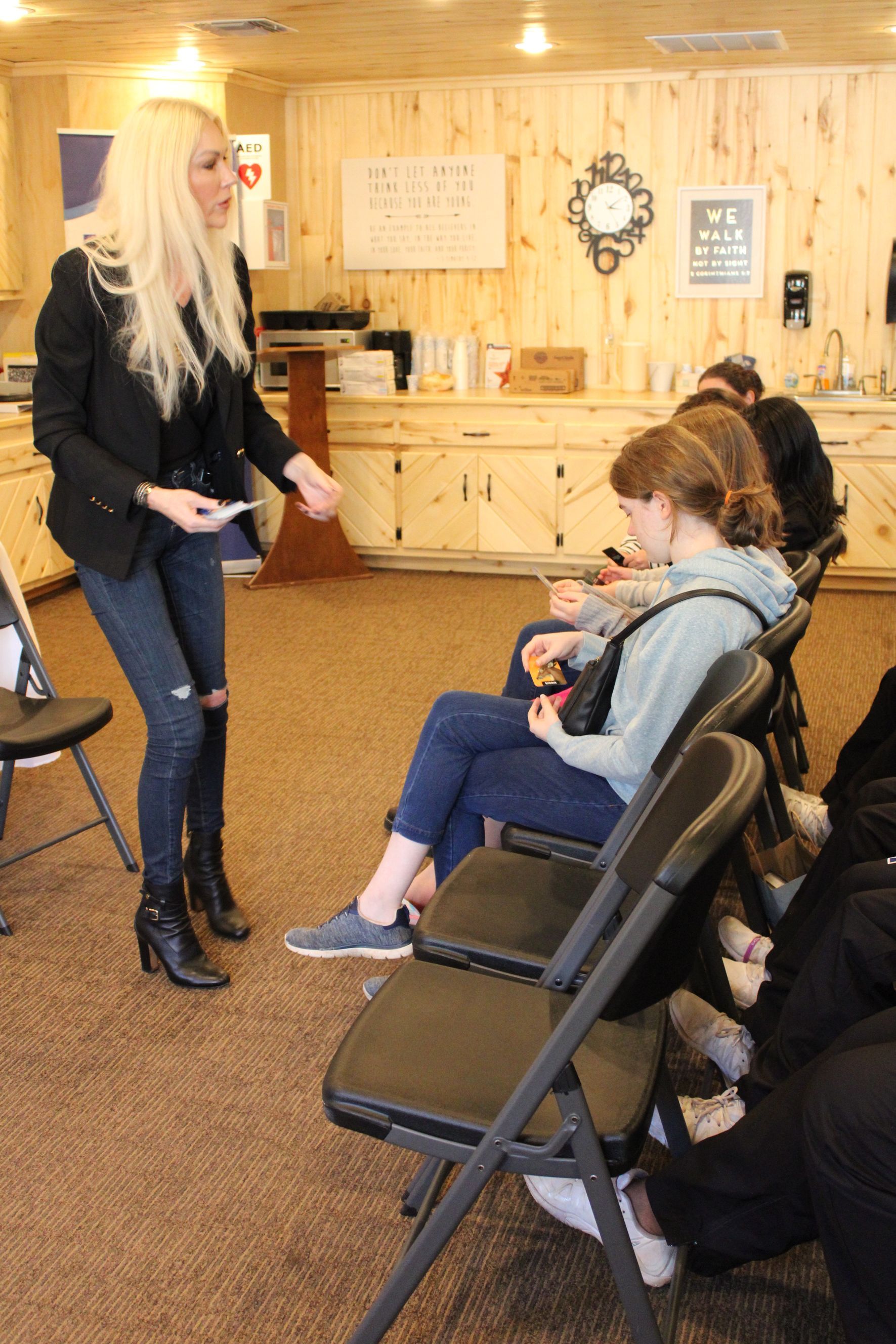 A woman is standing in front of a group of people sitting in chairs.
